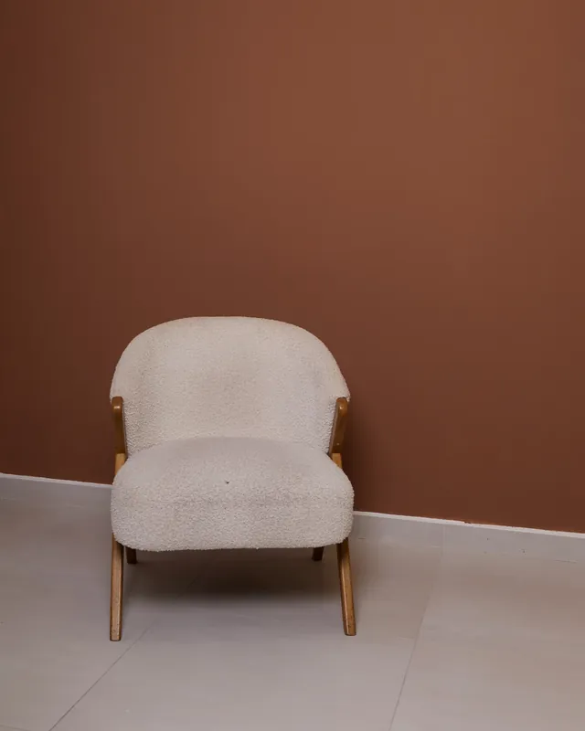 Poltrona de bouclé sobre fundo terracota, no estúdio